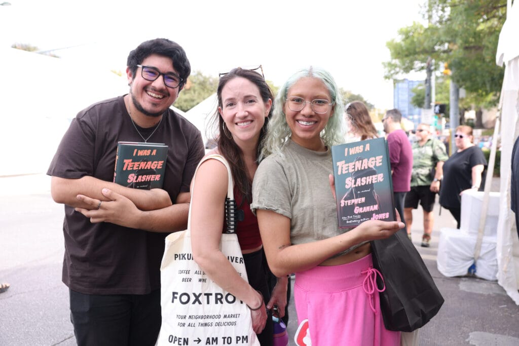 Three Texas Book Festival attendees smiling and holding books.